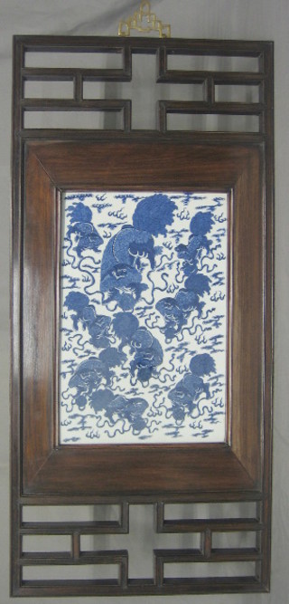 An 18th Century blue and white porcelain panel decorated dragons and contained within a hardwood panel, 17" x 10"