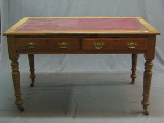 A honey oak writing table with red leather inset writing surface, fitted 2 frieze drawers, raised on turned supports 48"