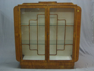 An Art Deco walnut display cabinet, the interior fitted adjustable shelves enclosed by astragal glazed panelled doors, 46"