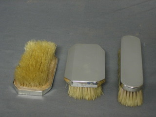 A pair of silver backed military hair brushes, London 1946 together with a silver backed clothes brush