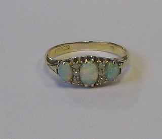 A gold dress ring set 3 oval cut opals supported by 6 diamonds