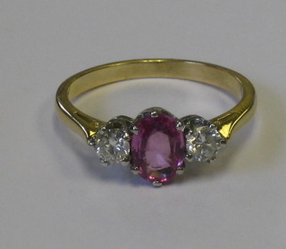 A lady's 18ct yellow gold dress ring set an oval cut pink sapphire supported by 2 diamonds