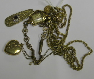An  oval gilt metal pendant set a red stone, hung on a gilt chain, a gilt metal pendant hung a St Christopher medal, a gilt metal chain hung a gilt locket and a lady's gold cased wristwatch