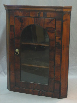 A 19th Century rosewood hanging corner cabinet with moulded cornice the interior fitted shelves enclosed by an arched glazed panelled door 27"