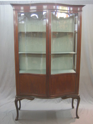 An Edwardian mahogany display cabinet of serpentine outline the interior fitted shelves enclosed by glazed panelled doors, raised on cabriole supports 41"