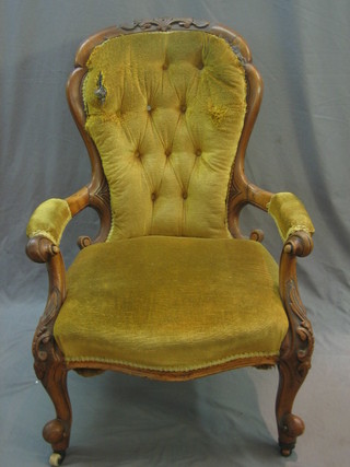 A Victorian carved walnut open arm chair raised on cabriole supports