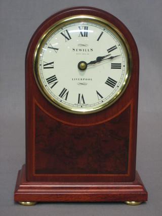 A Victorian style battery operated mantel clock by Sewills, contained in an arched inlaid mahogany case