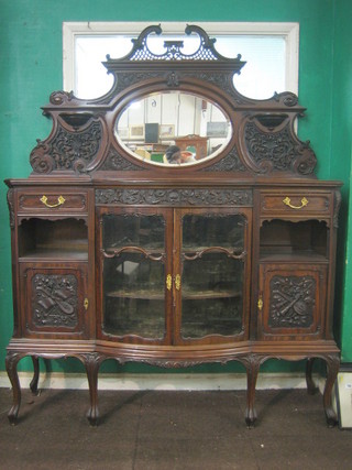 A Victorian carved mahogany chiffonier with raised mirrored back, the bow front base fitted a cupboard enclosed by a glazed panelled door flanked by 2 drawers above a recess, raised on cabriole supports 60"