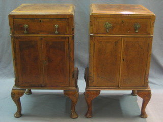A pair of Queen Anne style walnut bedside cabinets with feather banding fitted a drawer above a cupboard enclosed by a panelled door, raised on bracket feet 16"