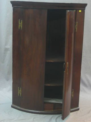 A Georgian mahogany bow front corner cabinet with moulded cornice, fitted adjustable shelves enclosed by panelled doors 30"