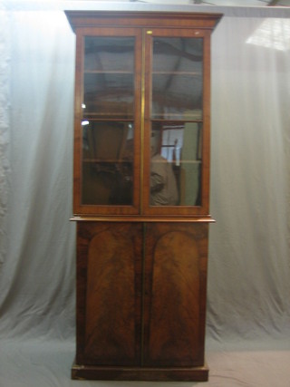 An associated Victorian mahogany bookcase on cabinet, the upper section fitted adjustable shelves enclosed by glazed panelled doors, the base fitted shelves enclosed by arch panelled doors, raised on a platform base 34"