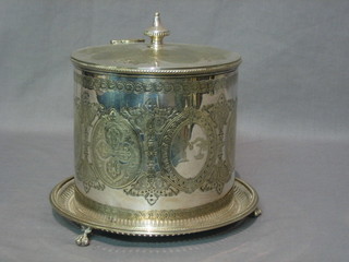 A circular engraved silver plated biscuit barrel with hinged lid and armorial decoration