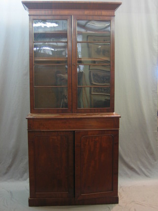 A Victorian mahogany bookcase on cabinet, the upper section with moulded cornice, the interior fitted adjustable shelves enclosed by glazed panelled doors, the base fitted 1 long drawer above a cupboard enclosed by panelled doors 39"