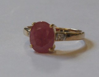 A "gold" dress ring set a red stone supported by 2 diamonds to the shoulders