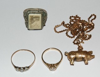 A collection of costume jewellery comprising 3 rings and a gold chain hung a pendant in the form of a pig