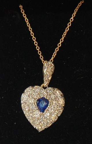 A gold heart shaped pendant set diamonds and a sapphire