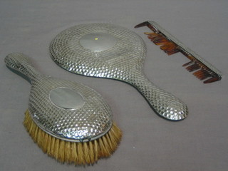 A planished white metal 3 piece dressing table set comprising hand mirror, hair brush and comb