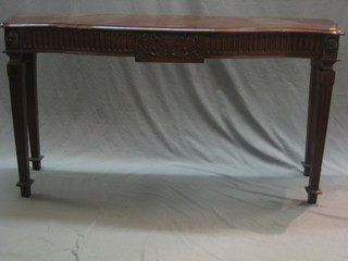 A 19th Century style mahogany side table of serpentine outline raised on square fluted supports ending in spade feet 56"