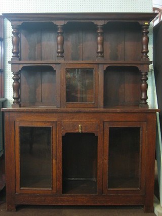 A Victorian oak dresser the raised back fitted shelves, the base fitted 1 long drawer above a recess flanked by a pair of double cupboards enclosed by glazed panelled doors 54"