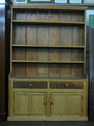An Irish pine dresser with moulded cornice, the raised back fitted 4 shelves, the base fitted 2 drawers above a double cupboard 54"