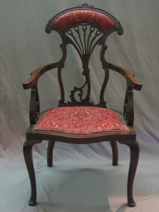 An Art Nouveau mahogany open arm chair of  with pierced vase shaped splat back and upholstered seat of serpentine outline, raised on cabriole supports