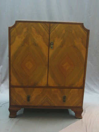 An Art Deco figured walnut tallboy enclosed by panelled doors, the base fitted 1 long drawer, raised on bracket feet 30"