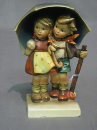 A Hummel figure of a standing boy and girl beneath an umbrella 7"