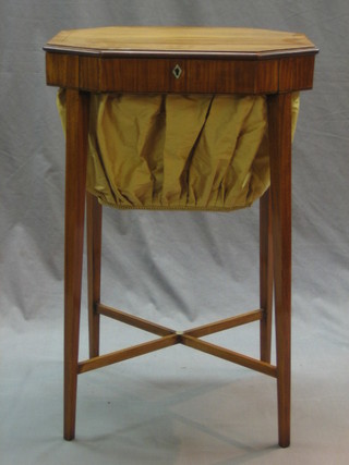 A Victorian lozenge shaped satinwood work table with hinged lid and ivory escutcheon, having a deep basket and raised on square tapering supports united by an X framed stretcher 19"