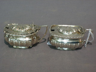 A matched pair of Victorian oval embossed silver mustard pots Birmingham 1876 and 1894 complete with blue glass liners, 4 ozs