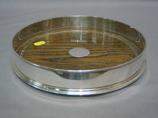A modern circular silver tray with bead work border and oak base 10"