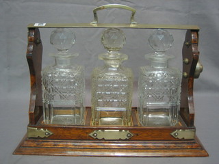 An oak and silver plated 3 bottle tantalus fitted 3 matched square hobnail cut decanters (1 stopper f)