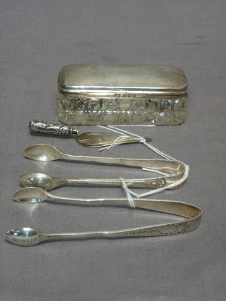 A rectangular cut glass dressing table jar with silver lid 3", 2 pairs of sugar tongs and a silver handled book mark in the form of a trowel