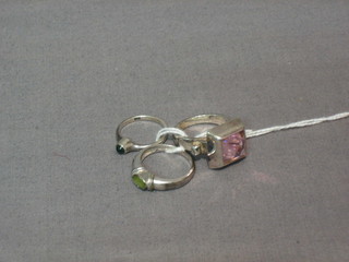 A 9ct white gold dress ring set an oval green stone, a silver dress ring set a blue stone and a silver ring set a pink stone