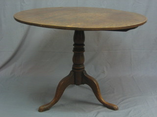 A 19th Century circular oak snap top tea table, raised on a turned column and tripod supports 34"