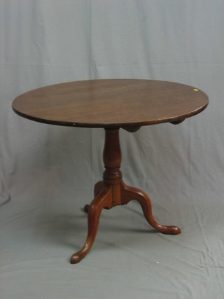 A 19th Century circular oak snap top tea table, raised on a turned column and tripod 38 1/2"