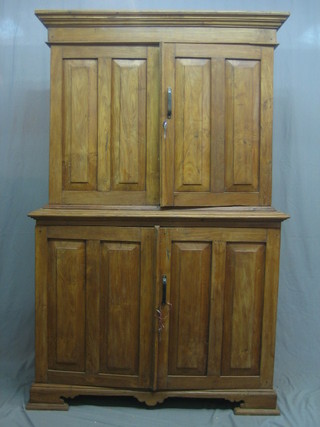 A hardwood cabinet on cabinet with moulded cornice the upper section fitted a cupboard enclosed by a panelled door, the base fitted a cupboard enclosed by a panelled door, raised on bracket feet 49"