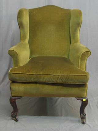A Victorian mahogany winged armchair, upholstered in green material, raised on cabriole supports