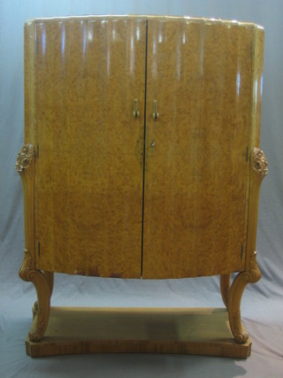 An Art Deco Birdseye maple shaped cocktail cabinet, the interior fitted drawers and cupboards, raised on carved cabriole supports 43"