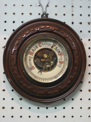 An aneroid barometer with porcelain dial contained in a carved walnut case 7 1/2" circular