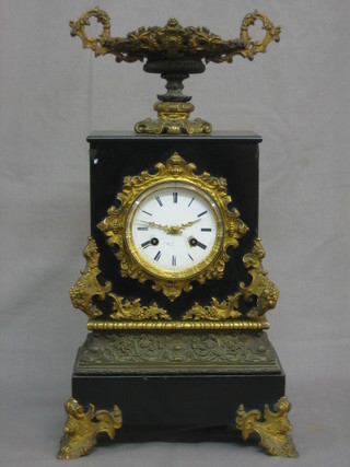 A French 8 day striking mantel clock with enamelled dial and Arabic numerals, contained in a marble gilt embellished case surmounted by a twin handled urn