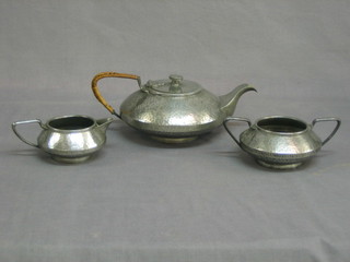 An Art Nouveau 3 piece planished pewter tea service by Unity  comprising teapot, twin handled sugar bowl and cream jug