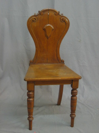 A Victorian oak shield back hall chair with solid seat, raised on turned supports