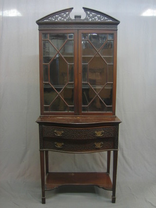 An Edwardian Chippendale style display cabinet, the top with pierced broken pediment and blind fretwork frieze, the interior fitted shelves enclosed by astragal glazed panelled doors, the bow front base fitted 2 long drawers and blind fretwork decoration, raised on square tapering supports ending in spade feet 30"