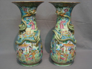 A handsome pair of Canton famille rose porcelain club shaped vases with flared mouths, the bodies decorated court scenes and dragons (slight chip to rim) 18"