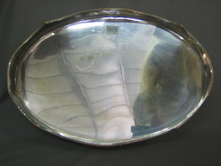 An oval silver plated twin handled tea tray with galleried decoration 18"