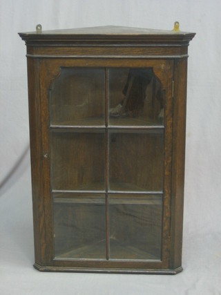 A 19th Century oak hanging corner cabinet with moulded cornice, the interior fitted shelves, enclosed by an astragal glazed panelled door 23"
