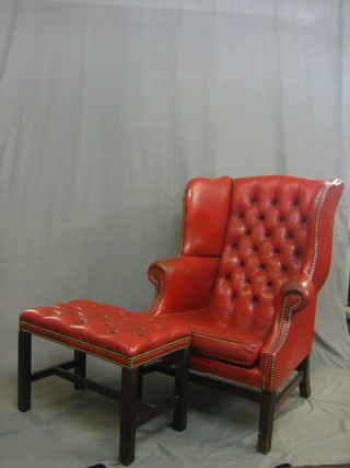A  Georgian style mahogany winged armchair upholstered in buttoned red material, raised on square supports, together with a matching footstool