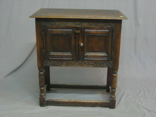 A 17th Century style oak cabinet enclosed by  panelled doors, raised on turned and block supports 27"