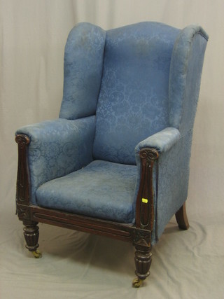 A William IV mahogany framed wing chair upholstered in blue material, raised on turned and reeded supports
