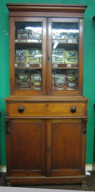 A Victorian mahogany bookcase on cabinet, the upper section with moulded cornice, the interior fitted adjustable shelves enclosed by a glazed panelled door, the base fitted 1 long drawer above a double cupboard enclosed by panelled doors, raised on hoof feet 38"